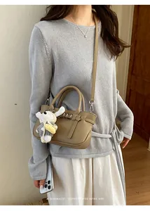 Elegante borsa tote minimalista in pelle kaki indossata come borsa a tracolla da una modella
