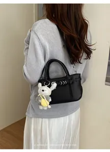 Borsa a tracolla nera testurizzata alla moda con un dolce ciondolo di coniglio bianco