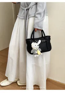Primo piano di una piccola borsa nera con un simpatico ciondolo a forma di coniglio bianco