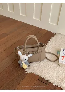 Squisita borsa tote piccola kaki con un simpatico portachiavi a coniglio sul pavimento