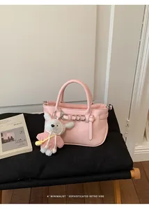 Dettaglio ravvicinato di una borsa a mano rosa in pelle martellata con ciondolo peluche