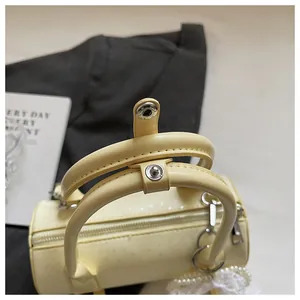 Close-up detail of yellow cylindrical handbag showing handles and snap button