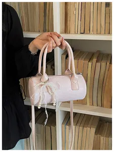 Close-up view of a pink cylinder handbag with delicate pearl and lace bow decorations