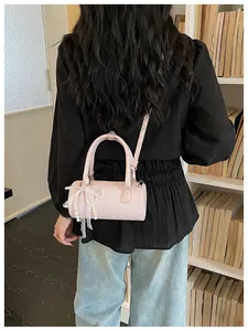Pink cylinder handbag with lace bow and pearl charm shown on a person's back