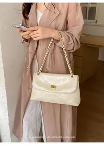 Model wearing a cream quilted chain shoulder bag with a minimalist retro vibe