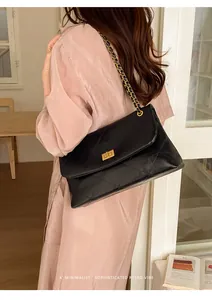 Detailed view of a black quilted chain shoulder bag worn by a model in a retro style setting.