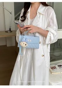 Detail of light blue quilted small square bag with cute bear charm and silver chain handle.