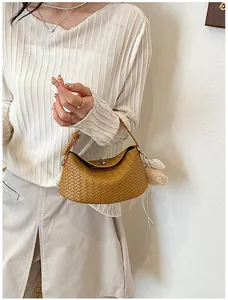 Brown woven leather hobo bag held by model, minimalist luxury style.