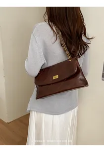 Detailed view of brown quilted chain shoulder bag worn by model in minimalist style
