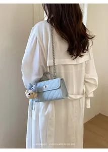 Back view of light blue quilted square bag with silver chain on model outfit