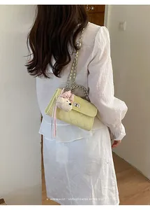 Close-up of a stylish yellow quilted crossbody bag with a cute bear charm accessory