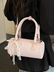 Elegant pink patent leather barrel handbag featuring a stylish lace and pearl bow accessory
