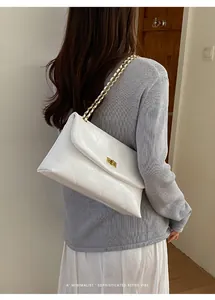 Close-up detail of a white quilted shoulder bag with sophisticated gold chain strap