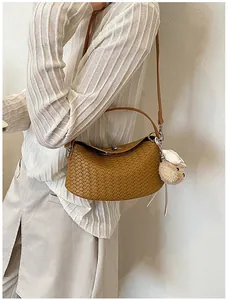 Elegant tan woven shoulder bag with cute bear charm shown in a stylish daily commute outfit