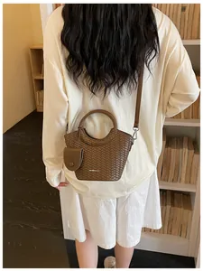 Elegant brown woven bucket bag with circular handle and adjustable crossbody strap