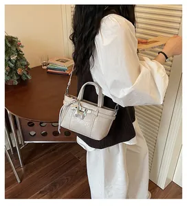 Detail view of a stylish beige textured bucket bag with horse charm in a cozy lifestyle setting.