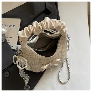 Vue détaillée d'un sac à main beige à volants avec breloque perle et motif écossais
