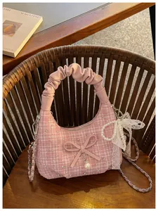 Détail macro d'un sac à main en tweed rose avec poignée plissée et décoration de nœud en perle.