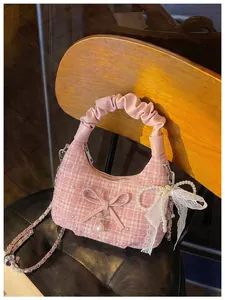 Détail exquis d'un sac à main en tweed rose avec nœud, perles et anse à volants.