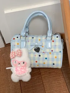 Elegante bolso de mano azul claro con lunares y un lindo llavero de conejo de peluche blanco