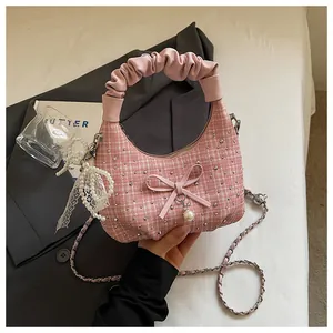Vue détaillée d'un sac à main en tweed rose avec poignée plissée et élégant nœud perlé.