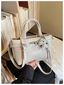 Close-up of beige wrinkled leather handbag with horse charm and adjustable strap.
