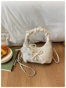 Détail du sac à main plissé crème avec un motif de tweed et des breloques en perles
