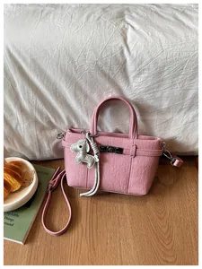 Close-up view of a pink crinkled leather bucket bag featuring a cute grey horse charm