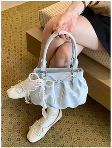 Detail view of light blue polka dot bucket bag with delicate lace and pearl charms.