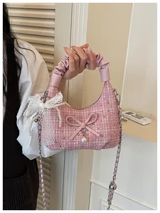Élégant sac à main en tweed rose avec nœud en perles et détails en dentelle tenu par une femme.
