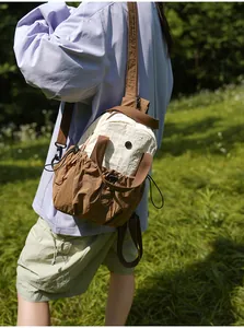 Multifunctional cream and brown crossbody bag shown in a natural outdoor setting.