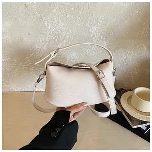 Dettaglio di borsa beige in pelle martellata con tracolla regolabile e fibbia
