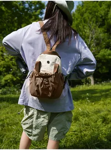 Back view of a woman carrying a lightweight brown and cream outdoor backpack in nature