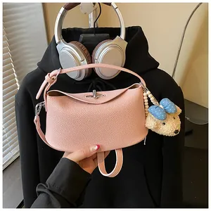 Vista dettagliata di una borsa rosa in pelle martellata con un grazioso ciondolo a forma di orso.
