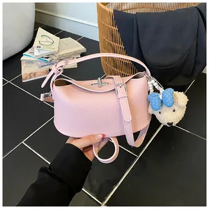 Dettaglio di una borsa a mano in pelle martellata rosa con un grazioso ciondolo a orsetto