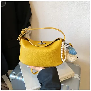 Primo piano di una borsa in pelle gialla martellata con eleganti ciondoli di perle.