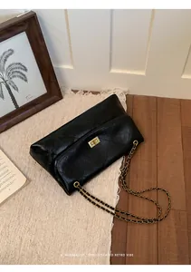 Detail shot of a black quilted chain handbag styled on a minimalist interior rug