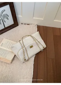 Detail view of a white quilted shoulder bag with gold chain and minimalist retro vibe