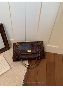 Retro brown quilted chain handbag with a gold-tone turn-lock closure on wooden floor.