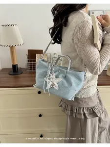 Close-up detail of a light blue denim handbag with a sparkling star charm and silver handles.