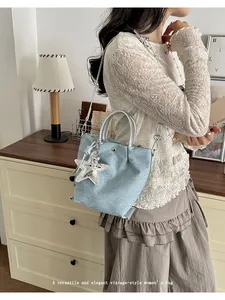 Stylish light blue denim dumpling bag featuring silver top handles and a cute star charm