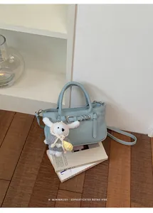 Vista dettagliata della mini borsa tote azzurra minimalista con ciondolo a forma di coniglio.