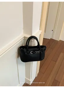 Elegante borsa a mano minimalista in pelle nera con fibbia e dettaglio ad anello.