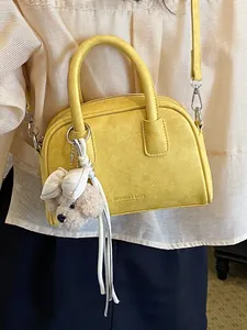Stylish vibrant yellow mini pillow bag with cute plush dog charm and shoulder strap