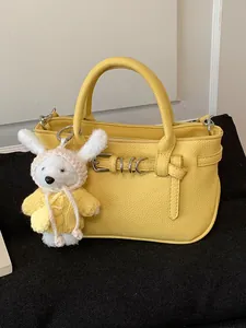 Elegante borsa a mano gialla in pelle con un grazioso ciondolo a forma di coniglietto bianco lavorato
