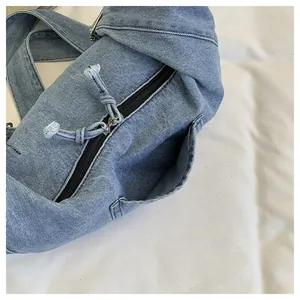 Macro view of blue denim dumpling bag showing zipper and textured fabric details