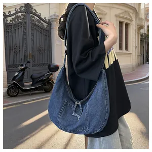 Lifestyle detail of a blue denim dumpling hobo bag worn as a crossbody shoulder bag.