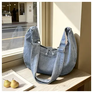 Large denim dumpling bag shown in detail on a wooden table with natural sunlight