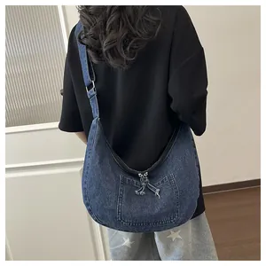 Back view showing a model wearing a large navy blue washed denim dumpling crossbody bag