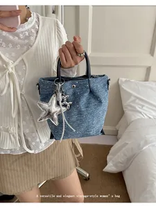 Detailed view of vintage blue denim dumpling bag with silver star and balloon dog charm